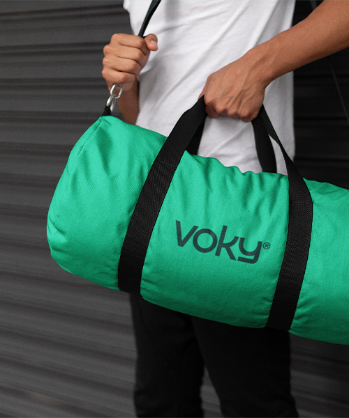 Närbild på en man som bär en grön duffelväska med Voky-märke