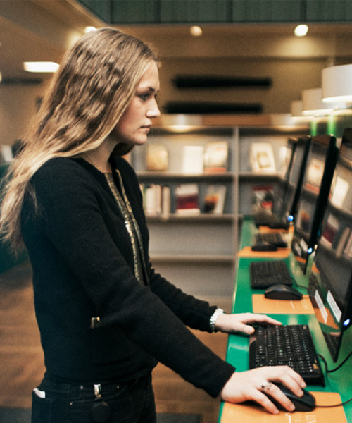 Kvinna som använder en dator stående på ett skrivbord.